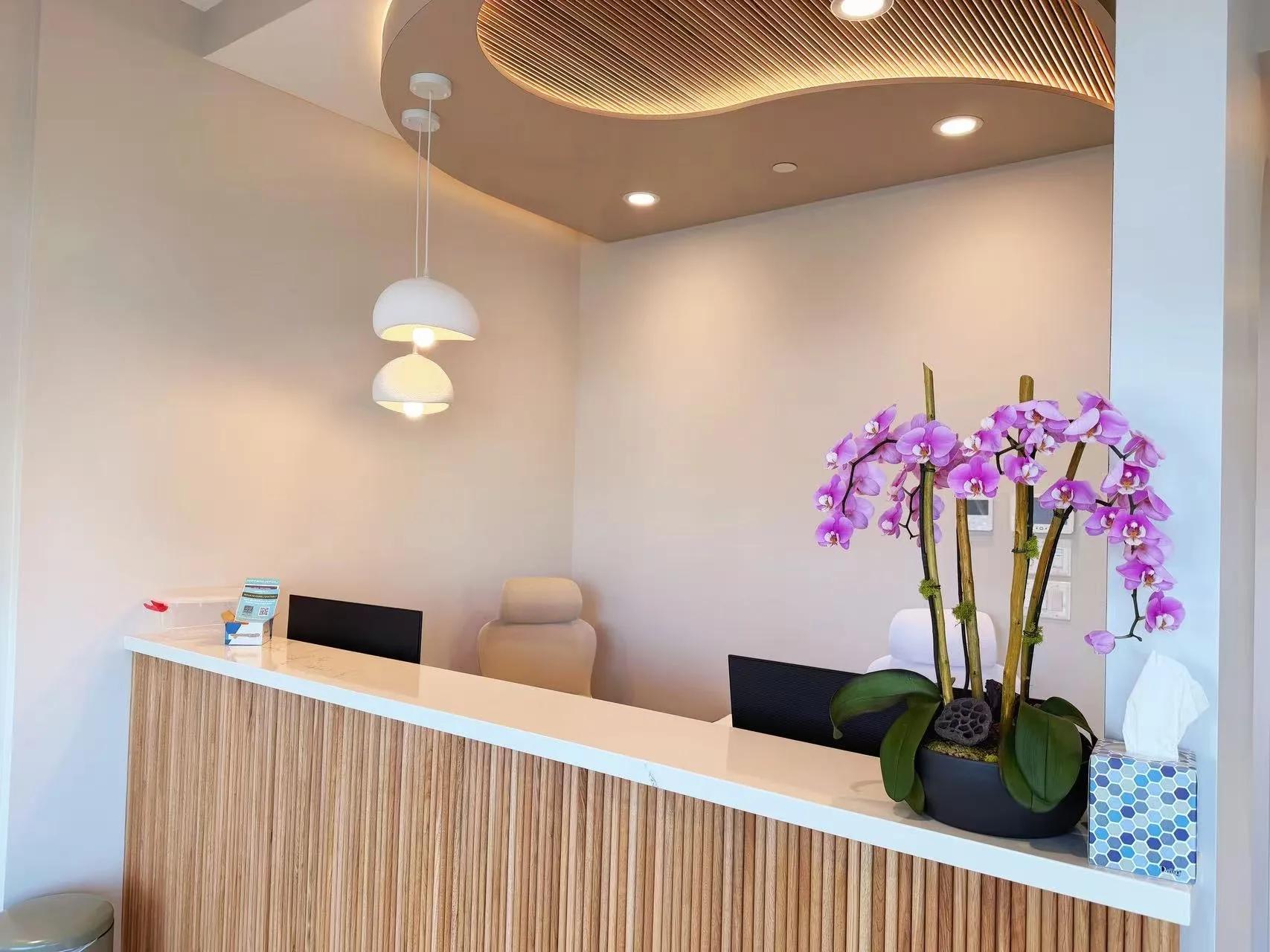 Coastal Light Dental reception with timber panels and orchids.